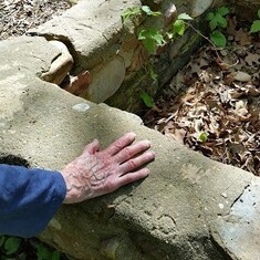 Mom's hand on the hearth her father built about 100 years ago. Notice her initials in the concrete.
