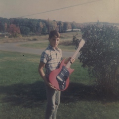 Tommy Cleveland holding a guitar that his Dad, Al made for him