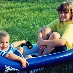 Cousins Sam Lukas and Audra Hagen, trying out an inflatable canoe on land at the lake home (1991).