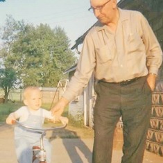 Grandpa Adolph Hagen helping Brent ride a tricycle in June 1965.