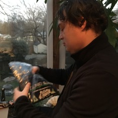 Brian opening Xmas gift in our family's sunroom. (That's part of the reason why his hair looks messy-- those are plant leaves). Maybe about 2014?