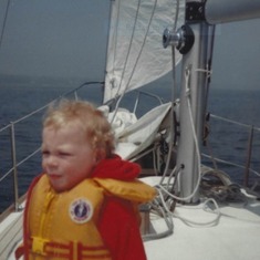 Brian, braced against the wind,  on sailboat as toddler