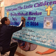Brody's Native Language teacher, Carmen, putting his name in Ojibway-Cree on the memorial banner.