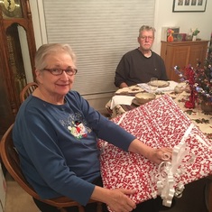 Camille and Ken opening a Christmas gift from daughter Stephanie.