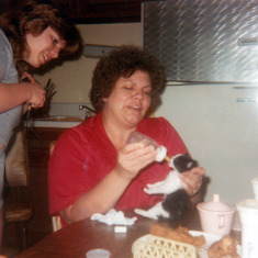 Carol feeding kitten (1983). Fried chicken wing and back on the table.