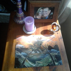 A memorial to Dana. A picture of us, a painting I gave her of an island scene, a glass heart with her ashes, a favorite bottle, and a lit candle.