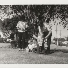 Nancy, Michael (looking through Easter basket, Ray and Don Hill under a tree