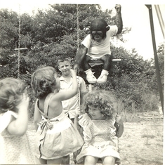 Dorinda on swing, sister Karen (Niriha) shaking hands with Muggs the monkey on swing above Dorinda