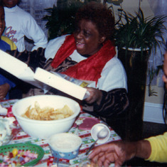 Mama opening up a Christmas gag gift at home 3636 Warder St., NW. Left to right Anthon Mama, and Clarence December 1989.