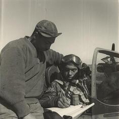 Pilot from the 332nd Fighter Group, signing form one book.