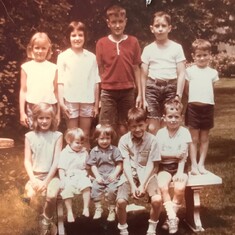 George J surrounded by cousins in Michigan circa 1965, sitting on the front row looking mischievous-