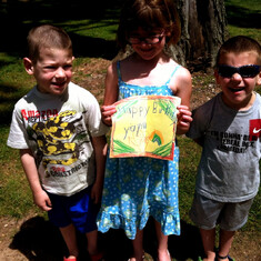 Remembering their grandma, Sean and Olga's kids Constantine, Tessa Eleni and Loukas visit Lily's final resting site with a hand-made Happy Birthday sign.