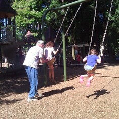 Herb pushing his granddaughters on the swings.