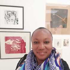 Ijeoma Uche-Okeke. Behind her are artworks by her parents Uche& Ego Okeke