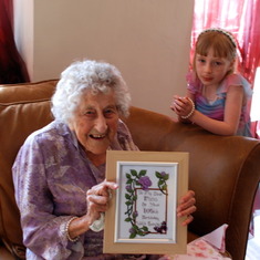Nana at her 105th Birthday party, holding the cross stitch created by Julie, with Lauren in the background.