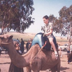 John riding a camel as a child. His father bestowed a love and appreciation for travel.