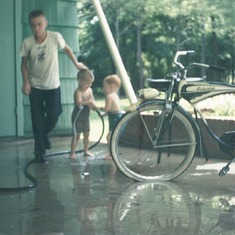 Jack got soaked attempting to settle a water dispute between Vic and his buddy Steven Brady .  Check out that Schwinn - -  Jack's first hot wheels! Jackson, Mississippi 1958