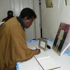 Mrs Dorothy Njeuma signing the condolence book