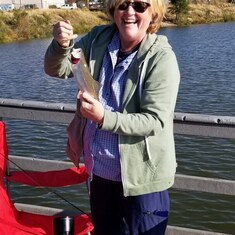 Judy fishing on her birthday this past year, with one of the two trout she caught.