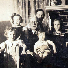 Kath in the arms of her grandfather, Paw O'Connor, in 1934 with Joan, Marge, Bill, and Tom