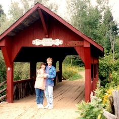 kim and doug pose in front of the covered bridge