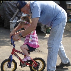 Teaching his granddaughter to ride a bike