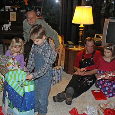 Dad watching kids open Christmas presents