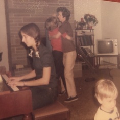 Laura playing the piano while Mom teaches Martha to dance.