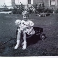 Lester's youngest, Sandra Kaye in a red Radio Flyer visiting a family farm outside of Brookings