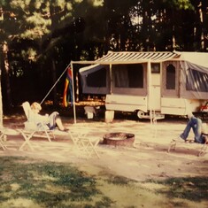 Camping and I am sure mom and dad put up the tent trailer with not a lot of help from the adults lounging in front