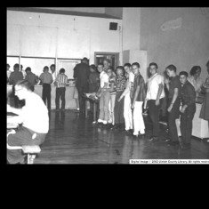 Dad in the middle school lunch room (front of the line, white shirt, smiling)