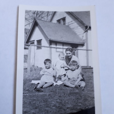 Backyard at Olds, 1932. L to R - Margaret, Willard standing and supported by Evelyn Bush, and Glenn