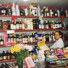 Mavis behind the counter of her off licence "Hackney Wine Corner".