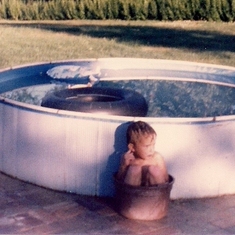 Our backyard pool.  The tub that Paul is sitting in contains water to rinse the dirt and grass off our feet before getting in.  Paul may be sitting in it because the water was warmer, or he wanted to keep me from being able to use it.