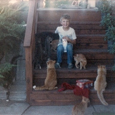 Paul surrounded by family farm cats. Their friendliness may have had something to do with his lunchbox that he had just brought home from school.