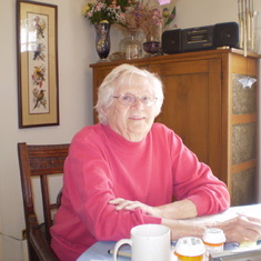 Phyllis at her 'nest' at her dining table in Joliet, ~2007.  She stitched the cross-stitched birds behind her.