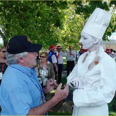 Telling jokes to a human statue to make her laugh at a Rotary Conference in Launceston  in 2009. He succeeded!