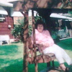 MOM ON THE SWING IN THE BACK YARD.
