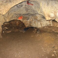 Sandi's foot disappearing in a crawl thru into Jobitzina cave. The orange paint are markers from previous explorers. Notice the black life line to d right