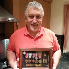 Joe shows the service medals awarded for wartime duty in the Merchant Navy. The brass inscription reads "Those who go down to the sea in ships, Who do business on great waters, They see the works of the Lord, And His wonders in the deep. Psalm 107:23-24"