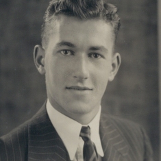 A dapper looking Charles in his early twenties, he is wearing the Merchant Navy emblem on the lapel of his jacket.