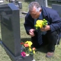 Charles's son Joe places flowers on his grave while being filmed for a report on BBC Wales evening news.