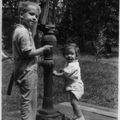 Stephen and his sister Mimi at the pump outside their cabin in Minnesota