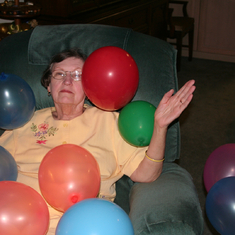 Sylvia playing with balloons piled on her.