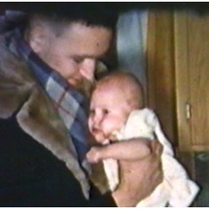 Colleen gets hug from Dad, home from work, late 1955 (still from family movie)