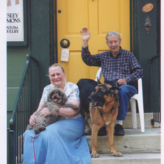 Ellen and Wesley waving from their porch with Max and Luger