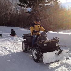 Dad on ATV pulling Ben & William on Snow Discs